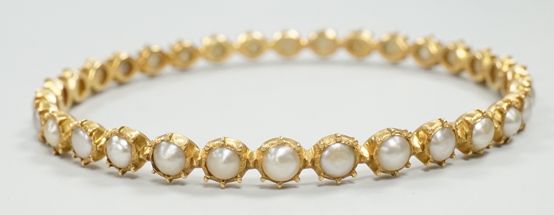 A modern yellow metal and split pearl set bangle, interior diameter approx. 58mm, gross weight 13.7 grams.